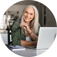 older woman next to laptop smiling