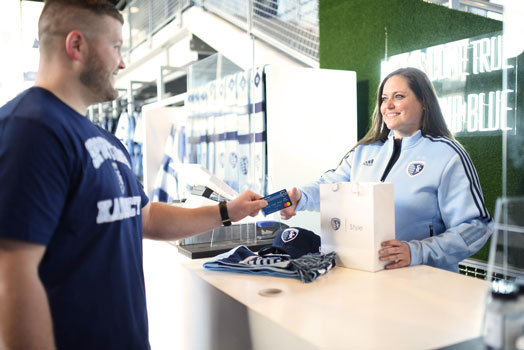 Image of a man paying with a Sporting KC debit card