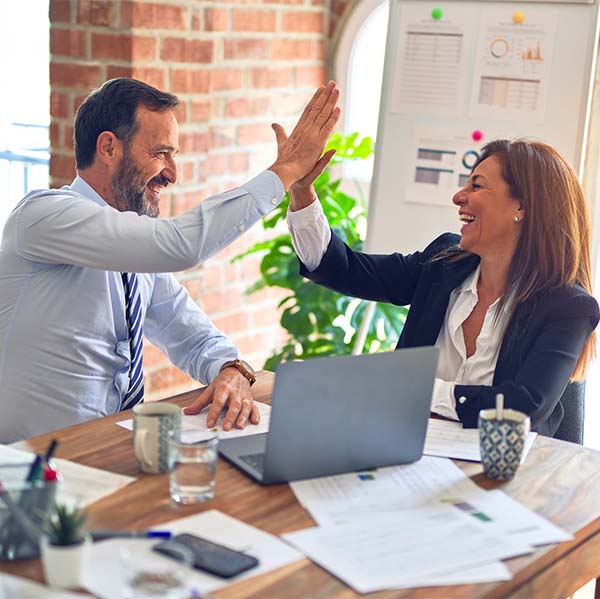 businessman and businesswoman high-fiving at table with papers