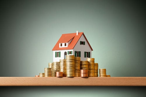 Model house with coins piled around 