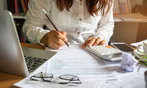 Woman filling out paperwork with calculator