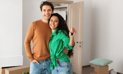 Happy couple showing house keys on moving day
