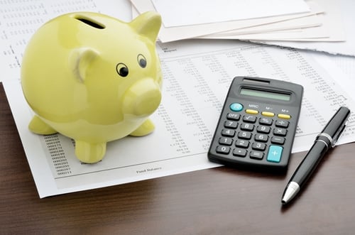 A piggy bank and calculator sitting on a table