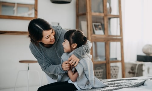 A parent and child sitting in a bedroom