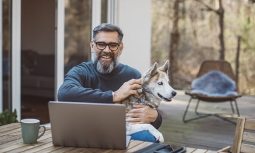 A person sitting on their back deck and using a laptop