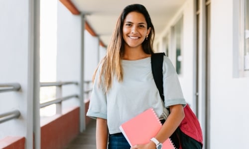 A college student standing in a building hallway