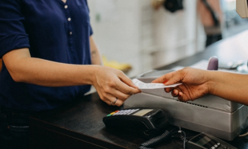 A cashier handing a shopper their receipt