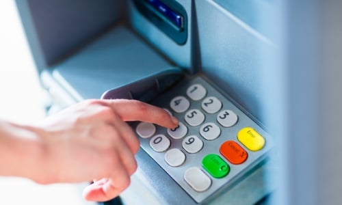 A person using the keypad on an ATM