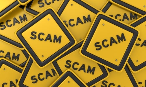 A pile of small yellow signs that all have the word scam