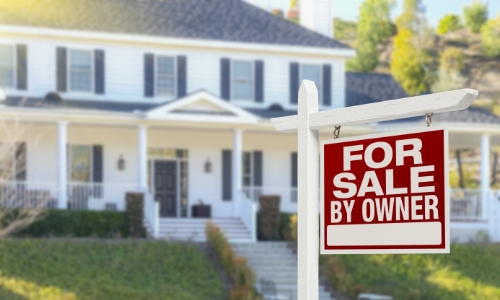 A house with a for sale by owner sign in the yard