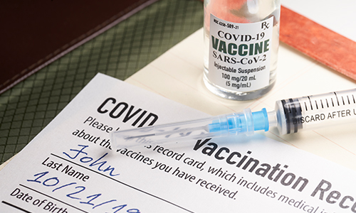 Covid-19 vaccination record card with syringe and vial.