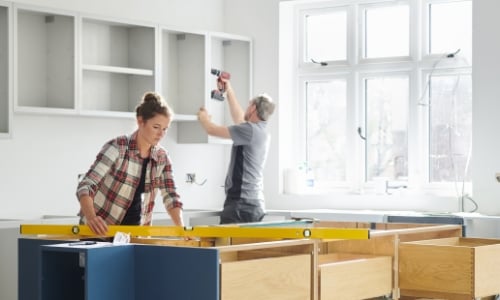 A couple installing new cabinets in their kitchen