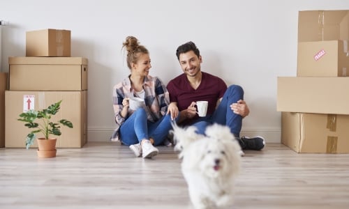 A couple sitting by moving boxes and enjoying their new home