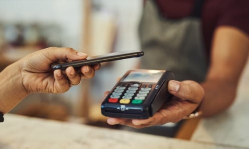 A person paying for a purchase in a store with their phone