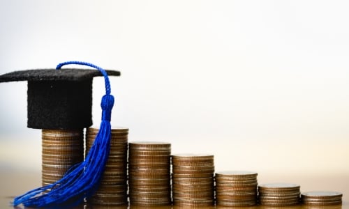 Stacks of coins with a graduation cap on top