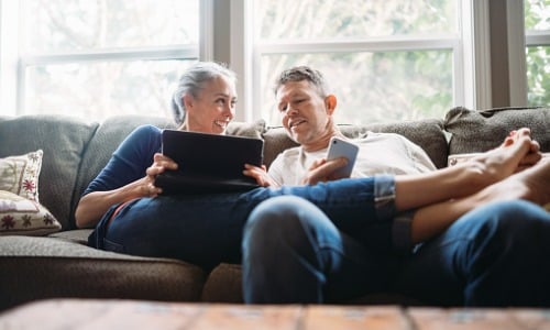 Mature couple relaxing with tablet and smartphone