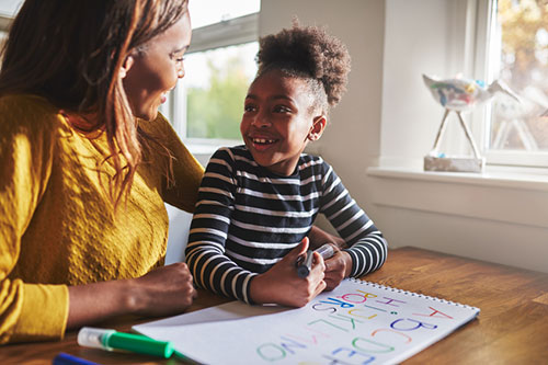 A mother and daughter sit together and color