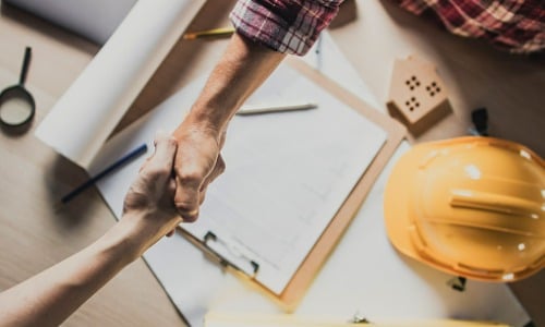 Two people shaking hands over table