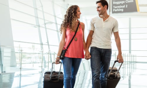 Couple at airport pulling luggage