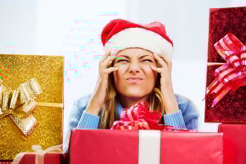 Woman surrounded by holiday presents and frustrated