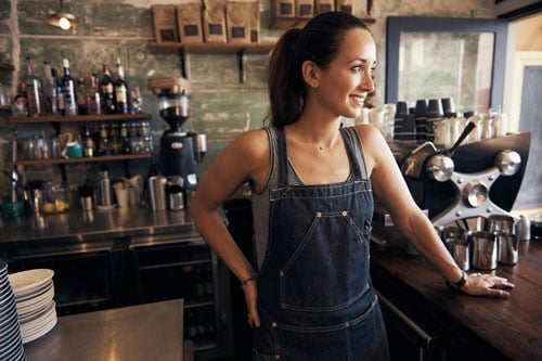 A woman standing behind the counter working at a coffee shop