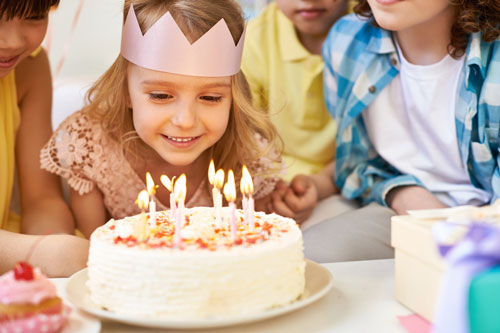 Young girl blowing out candles of her birthday cake