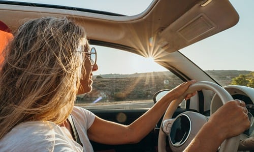 Young woman driving car at sunset