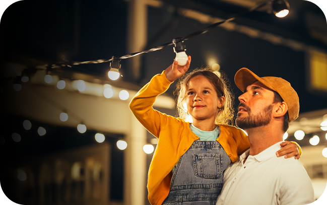 Child being held buy dad to screw in a lightbulb