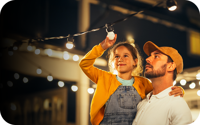 Child being held buy dad to screw in a lightbulb