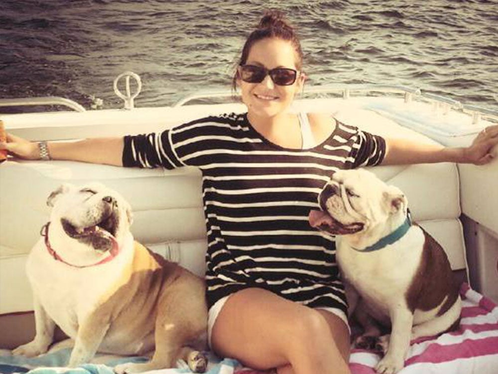 Beth with two english bulldogs sitting on a boat