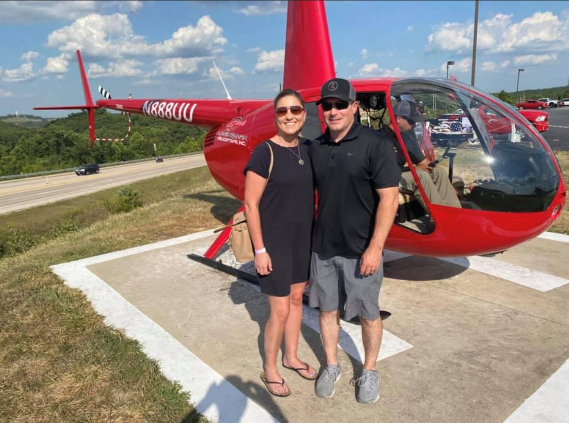 Amanda and her husband by a helicopter 