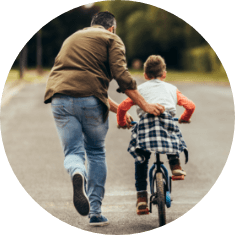 father teaching kid to ride bike