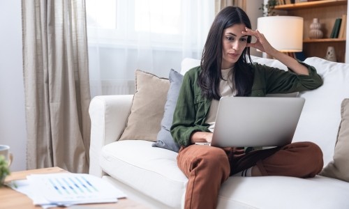 A woman browsing on her computer on the couch.