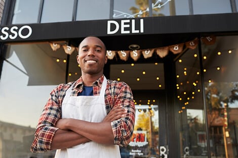 Grow your business today business owner standing in front of his deli