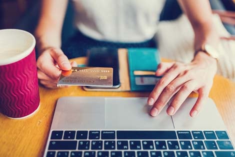 Woman using computer holding credit card