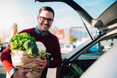 a man placing groceries in his car