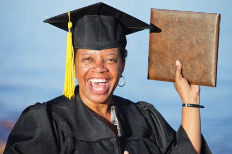Woman happily holding up her diploma