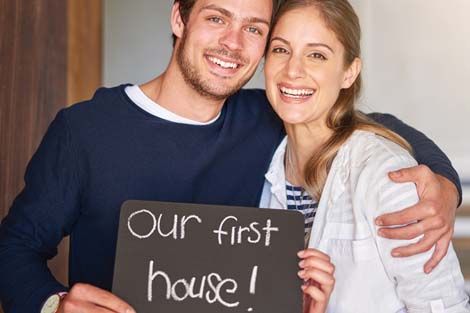 Couple holding sign that reads Our First House
