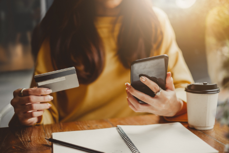 an individual making a purchase using their smartphone and credit card