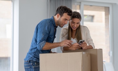 Couple using mobile app while moving into home