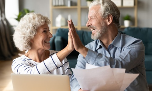 older couple high fiving, holding financial documents