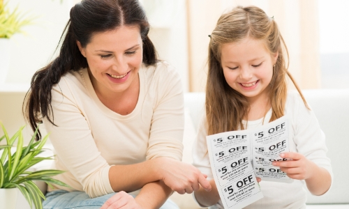 A parent and child cutting out coupons