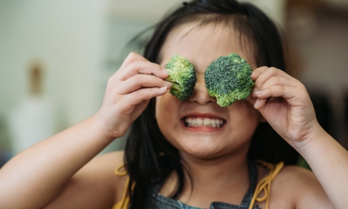 A child playing with broccoli