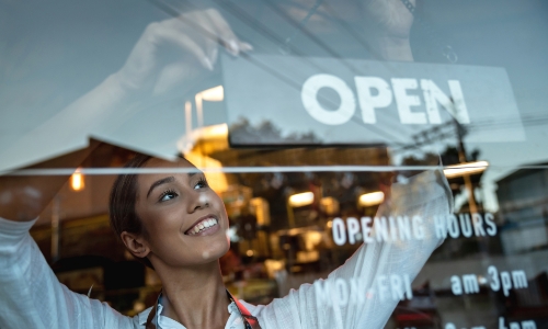 A business owner hanging an open sign in the window