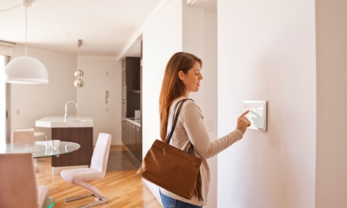 A person using a smart thermostat to change the temperature