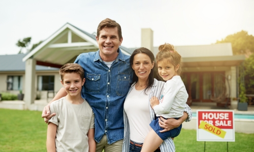 A family standing in front of a house they just bought