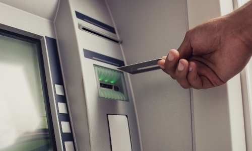 A person putting their card into an ATM
