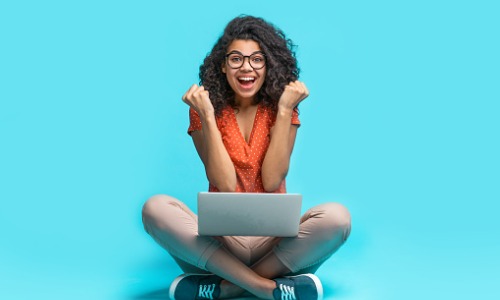 Excited college girl using laptop 