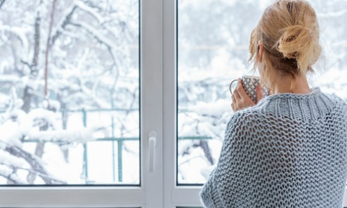 Woman in her home looking at the snow