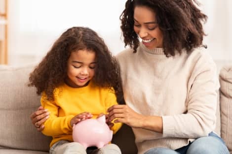 A mother and her daughter saving coins in a piggy bank